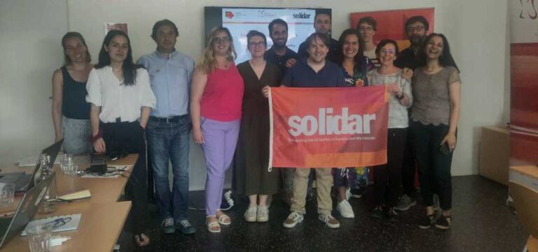 Participants to the Training Academy smile and hold SOLIDAR's flag